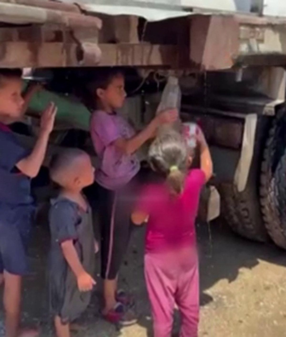 Gazzeli çocuklar kamyondan akan kirli suyu kaplara doldurmaya çalıştı